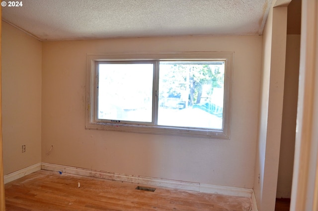 unfurnished room with a textured ceiling, light hardwood / wood-style floors, and a healthy amount of sunlight