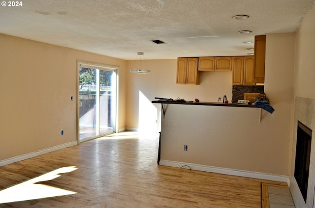 kitchen featuring a breakfast bar, tasteful backsplash, pendant lighting, and light hardwood / wood-style flooring