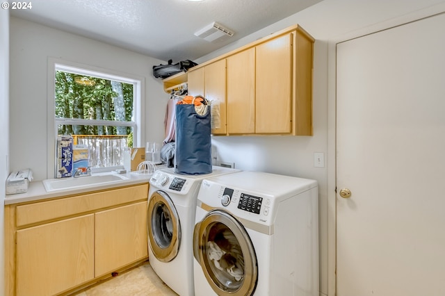 laundry area with washing machine and dryer, cabinet space, a sink, and visible vents