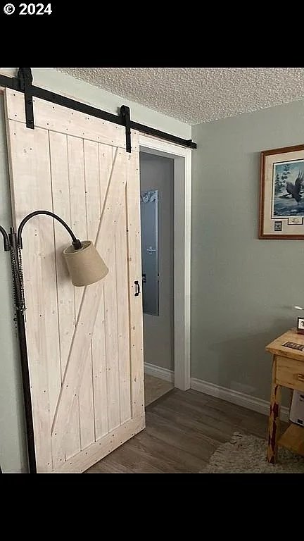 room details with a textured ceiling, a barn door, and wood-type flooring