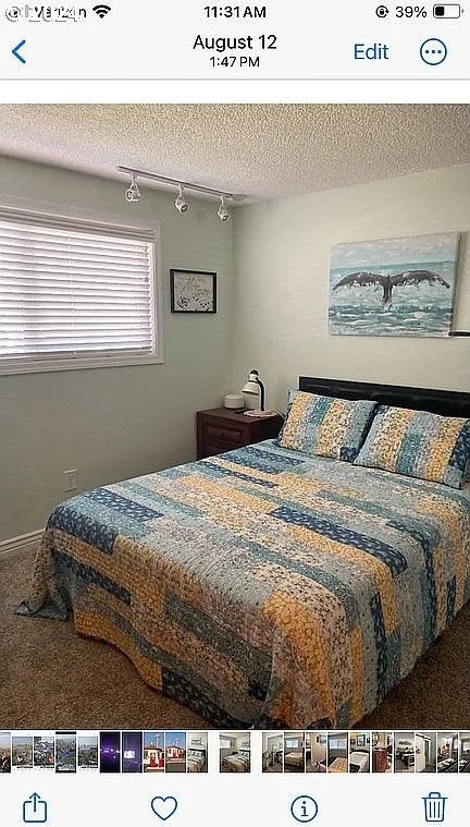 carpeted bedroom featuring a textured ceiling and rail lighting