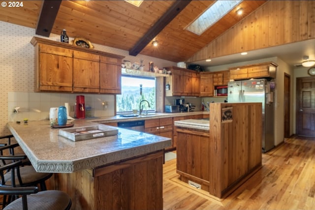 kitchen with a skylight, beamed ceiling, wood ceiling, stainless steel appliances, and kitchen peninsula