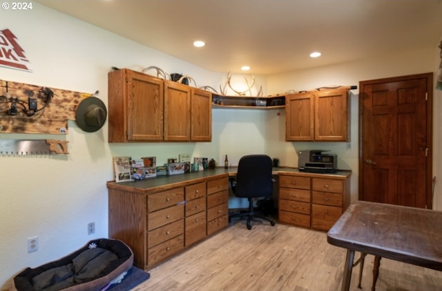 home office with built in desk and light hardwood / wood-style floors