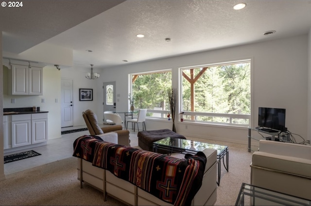 carpeted living room featuring a textured ceiling, a healthy amount of sunlight, and an inviting chandelier