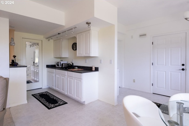 kitchen featuring sink, light tile floors, and white cabinetry