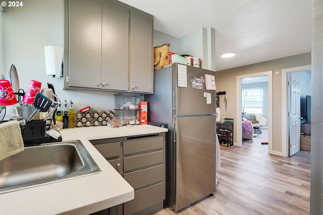 kitchen featuring stainless steel refrigerator, gray cabinetry, light hardwood / wood-style floors, and sink