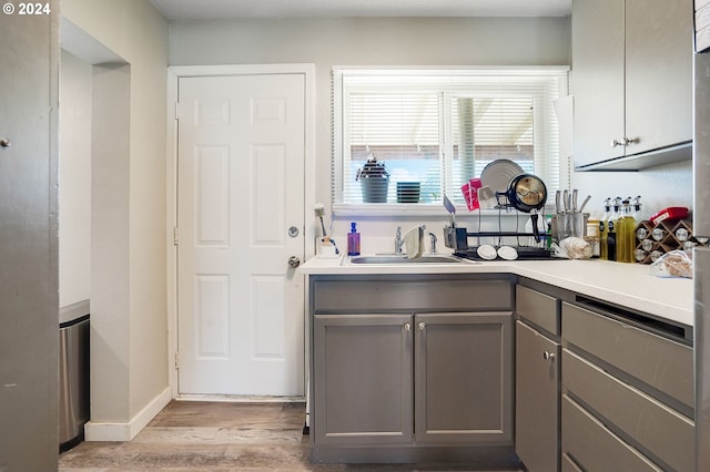 kitchen featuring light wood-type flooring, gray cabinetry, and sink