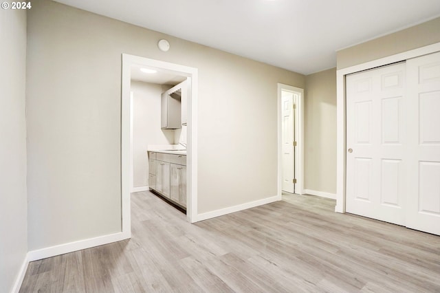 unfurnished bedroom featuring a closet, light hardwood / wood-style floors, and ensuite bath