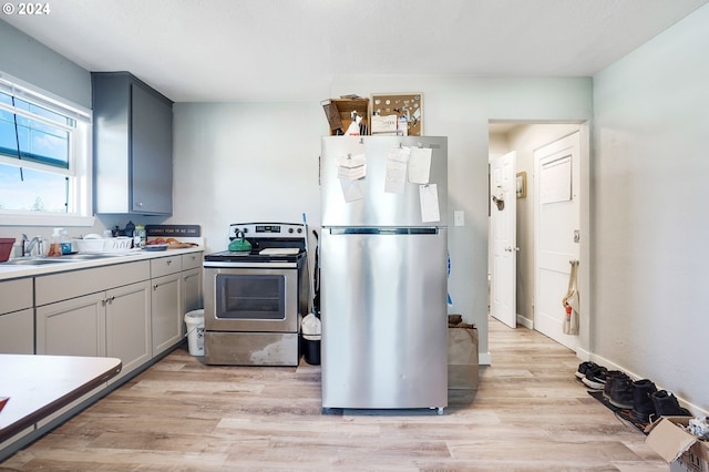 kitchen with appliances with stainless steel finishes, gray cabinets, sink, and light hardwood / wood-style floors