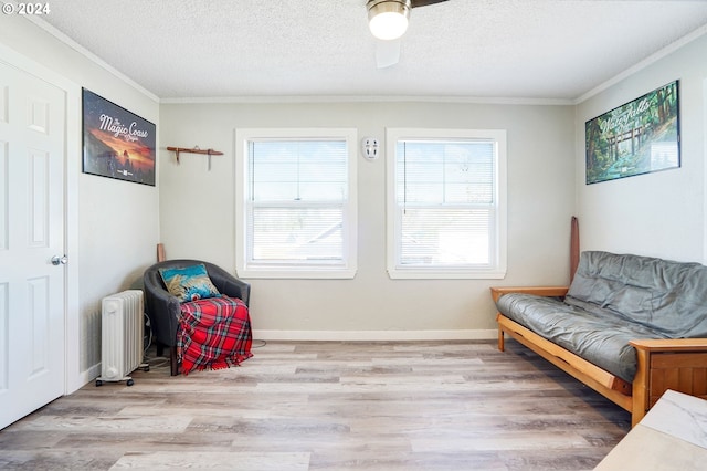 sitting room with crown molding, hardwood / wood-style floors, radiator, ceiling fan, and a textured ceiling