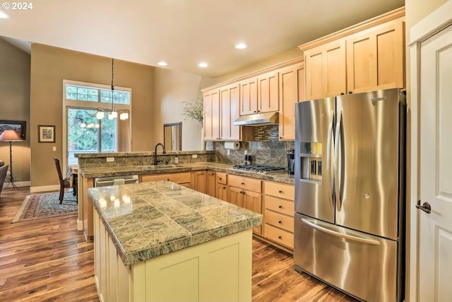 kitchen with sink, light hardwood / wood-style floors, hanging light fixtures, appliances with stainless steel finishes, and backsplash