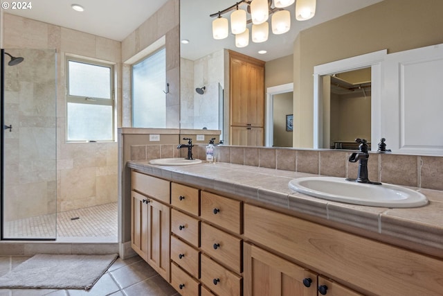 bathroom with tile patterned flooring, vanity, and tiled shower