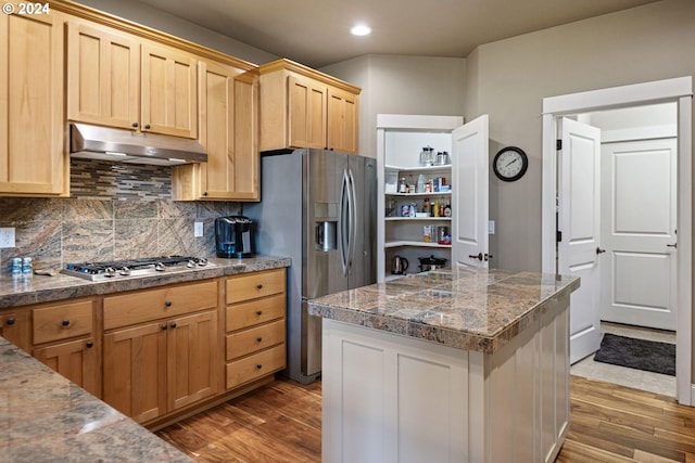 kitchen featuring light brown cabinetry, backsplash, stainless steel appliances, dark hardwood / wood-style floors, and a center island