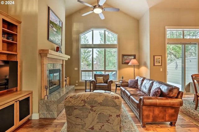 living room with a premium fireplace, high vaulted ceiling, ceiling fan, and light hardwood / wood-style floors