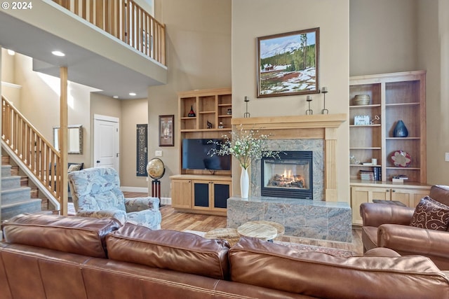 living room featuring wood-type flooring, a fireplace, and a towering ceiling