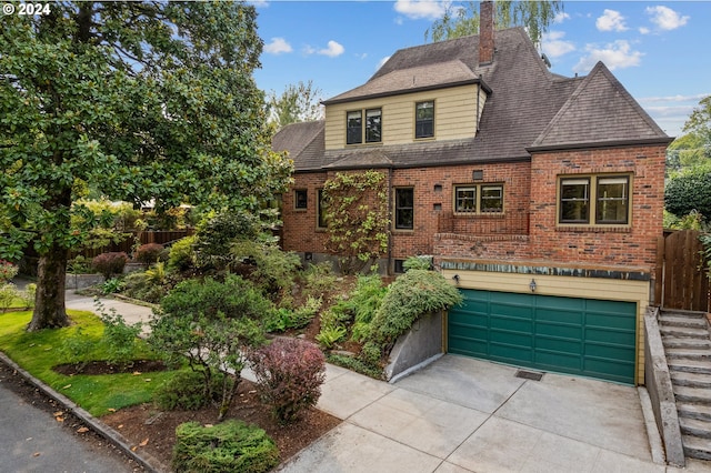 view of front of house with an attached garage, fence, concrete driveway, and brick siding