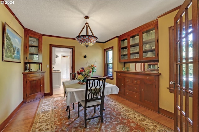 dining area with hardwood / wood-style floors, crown molding, and a textured ceiling