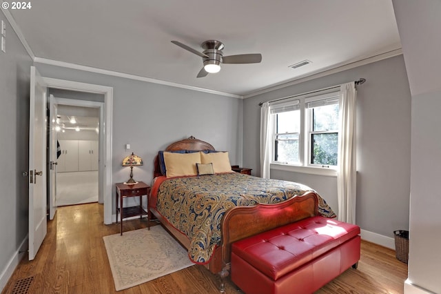 bedroom featuring baseboards, wood finished floors, visible vents, and crown molding