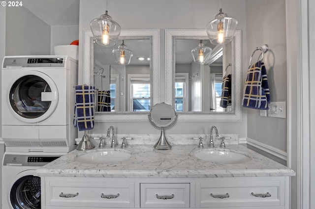 full bathroom featuring double vanity, stacked washing maching and dryer, and a sink