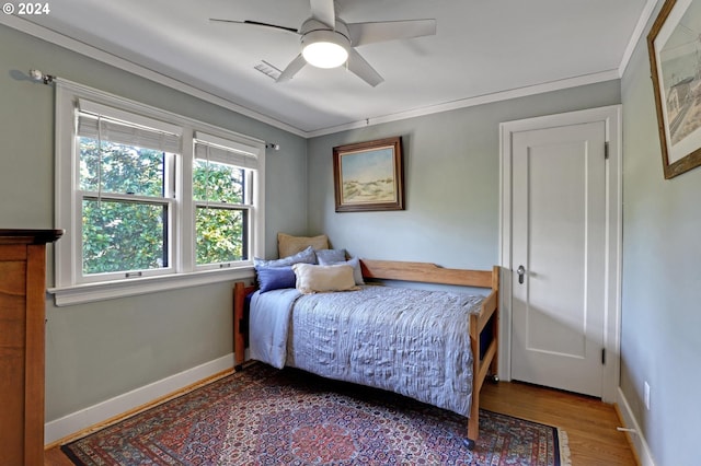 bedroom featuring ornamental molding, ceiling fan, baseboards, and wood finished floors