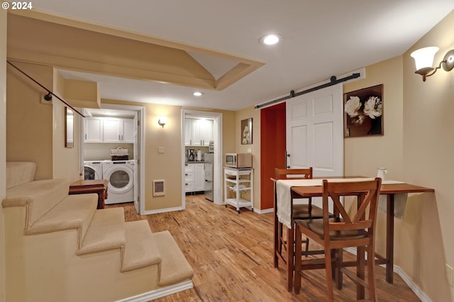 interior space with a barn door, visible vents, stairs, light wood-type flooring, and washer and clothes dryer