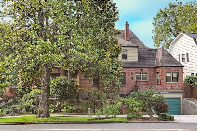 view of front facade with driveway, an attached garage, a chimney, and brick siding