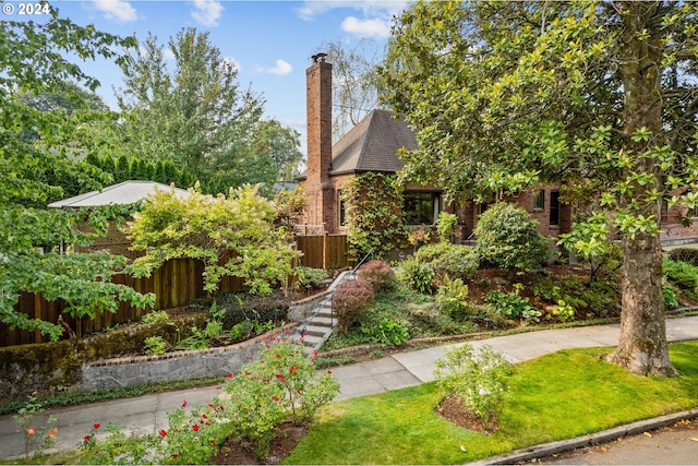 view of front of property featuring brick siding, roof with shingles, and fence