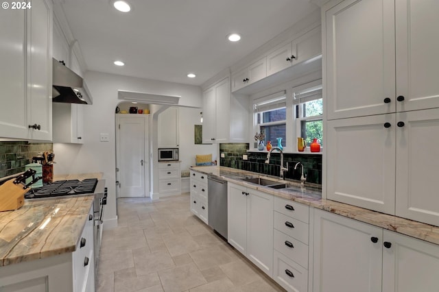 kitchen featuring stainless steel appliances, range hood, white cabinets, and tasteful backsplash