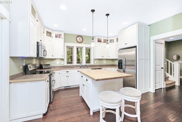 kitchen with white cabinetry, appliances with stainless steel finishes, a center island, and dark hardwood / wood-style floors