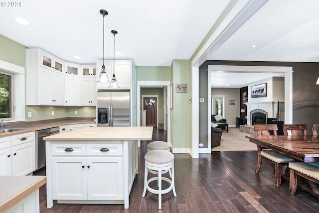 kitchen with dark hardwood / wood-style floors, a center island, decorative light fixtures, white cabinetry, and appliances with stainless steel finishes