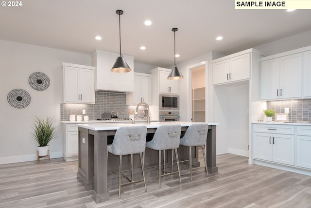 kitchen featuring white cabinetry, appliances with stainless steel finishes, a center island with sink, and pendant lighting