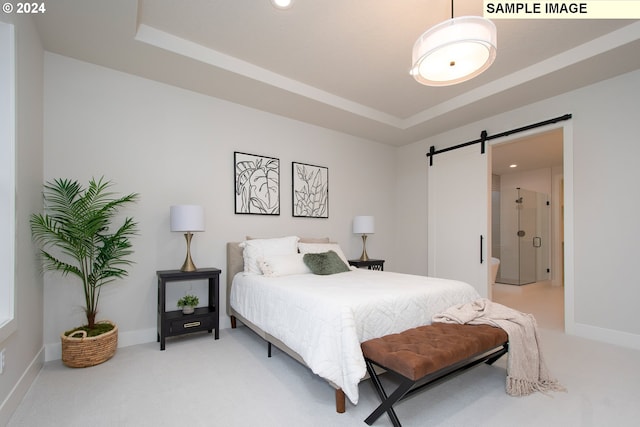 carpeted bedroom with a tray ceiling and a barn door