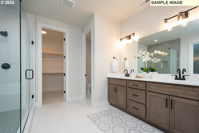 bathroom with vanity, toilet, tile patterned flooring, and a shower with door