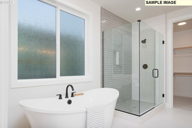 bathroom featuring recessed lighting, a walk in closet, a soaking tub, and a stall shower