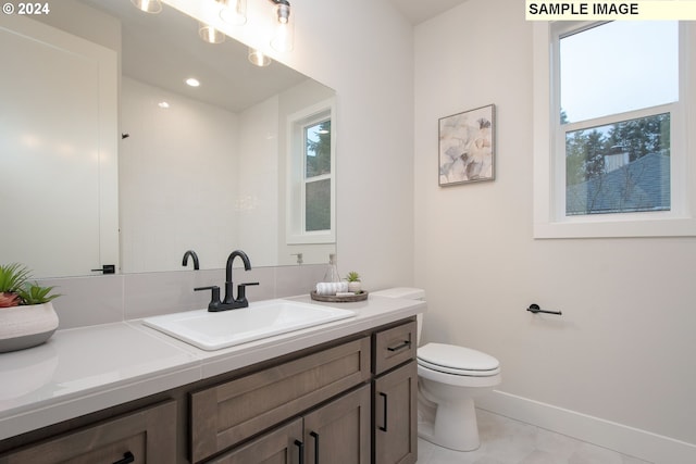 bathroom with a healthy amount of sunlight, vanity, toilet, and tile patterned flooring