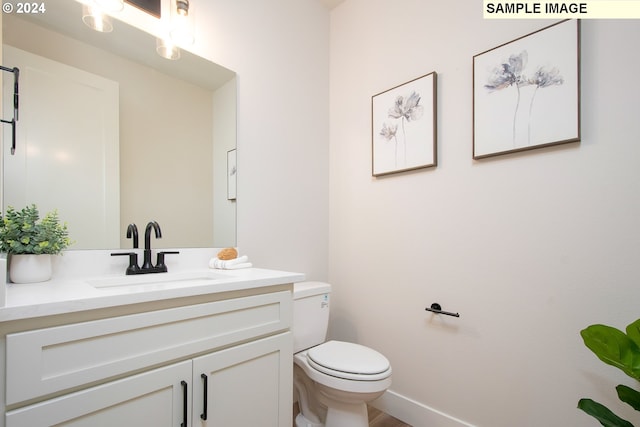 bathroom with toilet, vanity, and baseboards