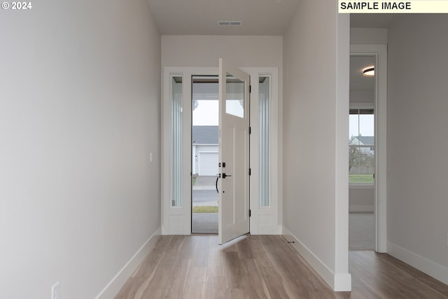 foyer entrance with light wood-style flooring, visible vents, and baseboards