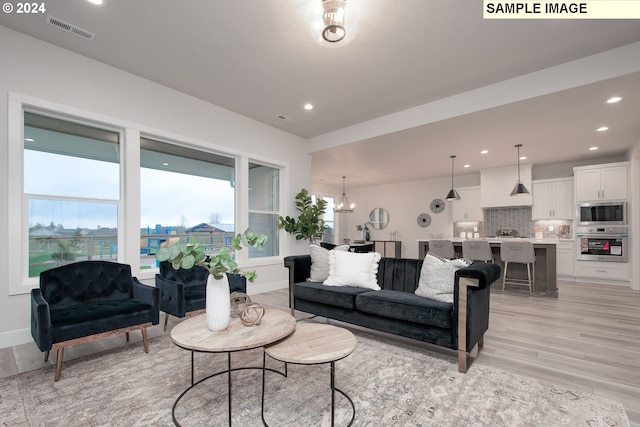 living room with a wealth of natural light, light hardwood / wood-style floors, and a chandelier