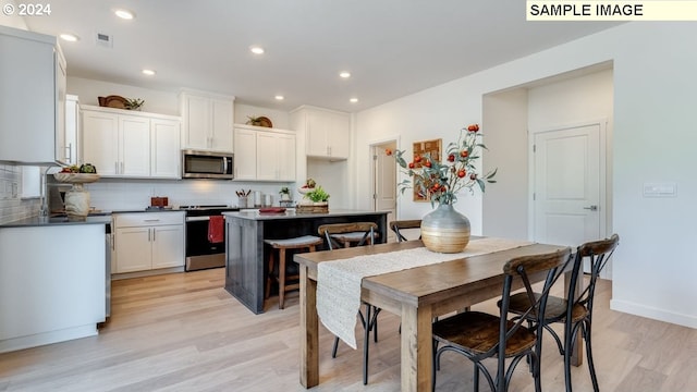 kitchen with stainless steel appliances, backsplash, and light wood finished floors