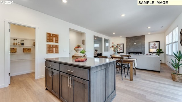 kitchen with recessed lighting, a fireplace, a kitchen island, light countertops, and light wood-type flooring