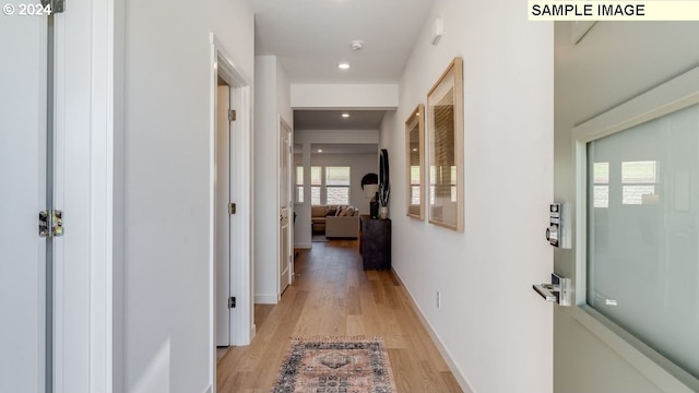 corridor featuring light wood-type flooring, baseboards, and recessed lighting