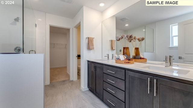 bathroom featuring double vanity, a shower stall, visible vents, and a sink