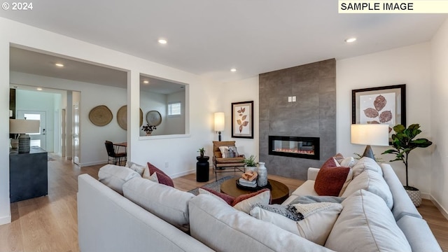 living area with light wood finished floors, recessed lighting, baseboards, and a tile fireplace