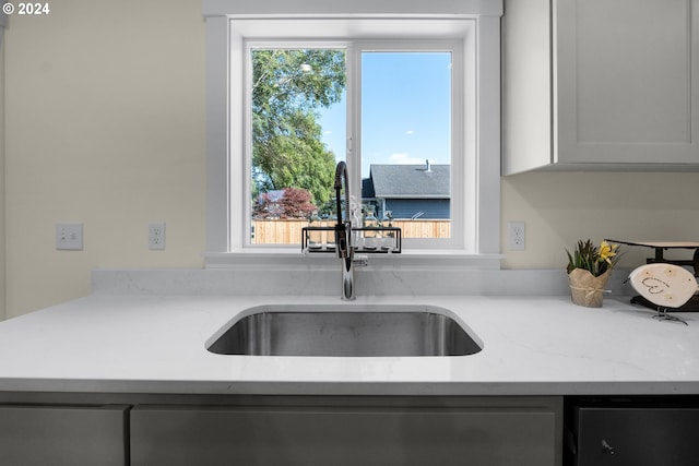 kitchen featuring light stone counters, white cabinets, sink, and plenty of natural light