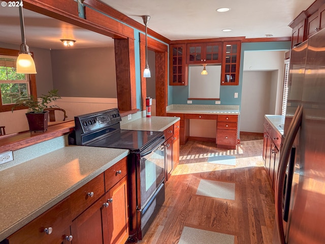 kitchen with pendant lighting, high end refrigerator, black electric range oven, and light wood-type flooring