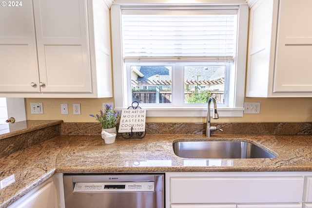 kitchen with stone counters, sink, white cabinets, and stainless steel dishwasher