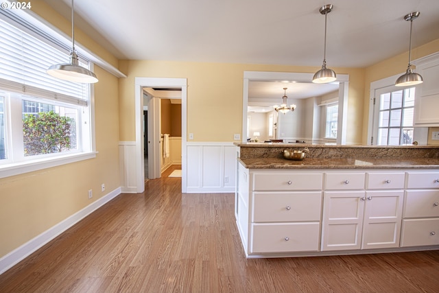 kitchen with white cabinetry, plenty of natural light, dark stone counters, and light wood-type flooring