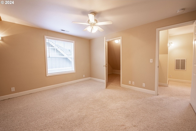 unfurnished bedroom featuring a walk in closet, ceiling fan, and light carpet