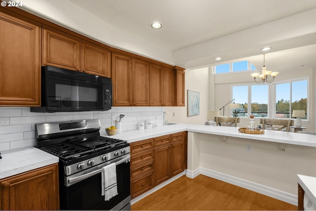 kitchen featuring light countertops, black microwave, brown cabinets, and stainless steel gas range oven