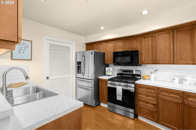 kitchen with stainless steel appliances, a sink, light countertops, and brown cabinets